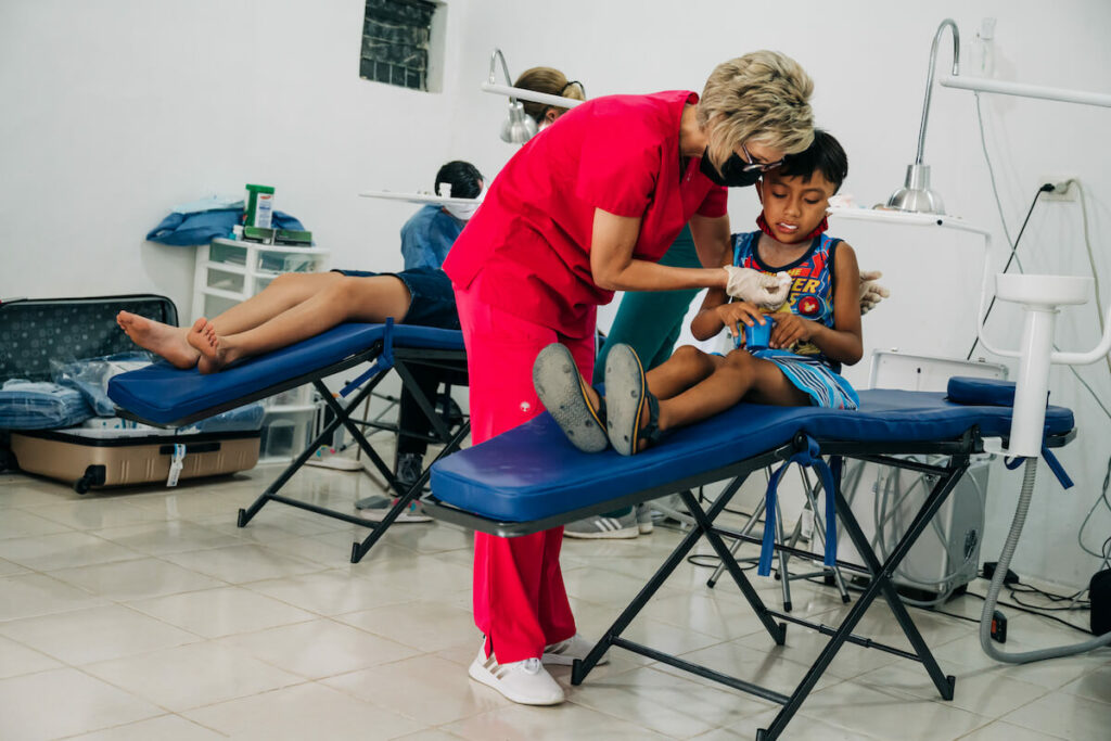 Assistant helps a young male patient with packing gauze in his mouth. Learning to navigate these difficulties with patience and compassion early in your career can prepare you for true greatness.