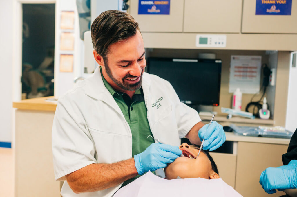 Smiling dentist working on young male's teeth. You'll need to be inside your patients' personal space, sometimes for long periods.