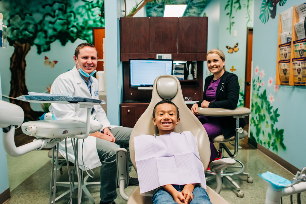 Smiling CDP doctor, hygienist and young child in dental office setting.