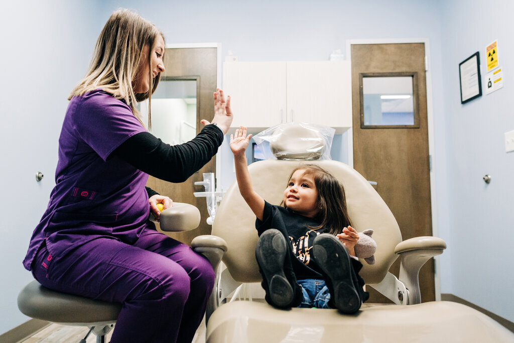 CDP hygienist giving a young patient a high-five.