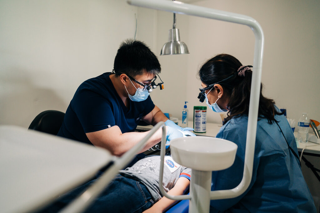 A CDP Oral Surgeon working on patient as a hygienist assists.