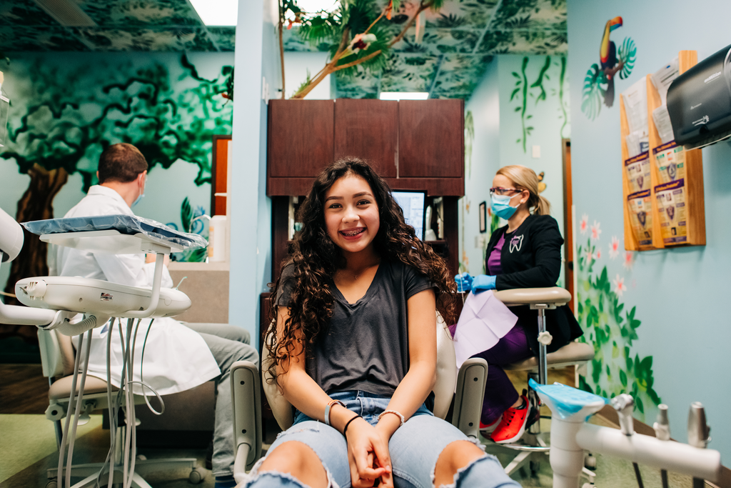 Young, smiling ortho patient sitting in a dental chair.